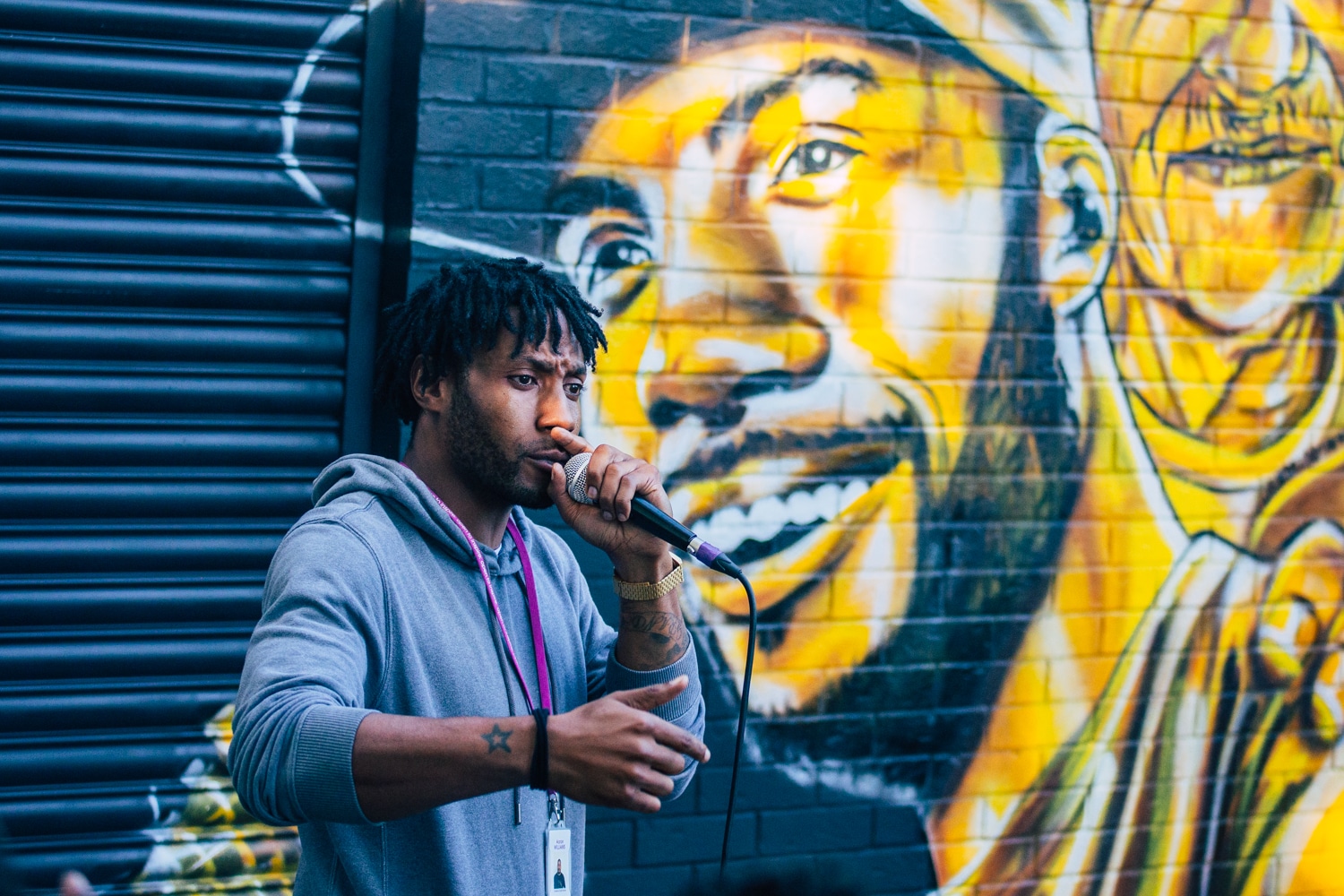 Aaron Williams speaking in front of a gold mural of himself